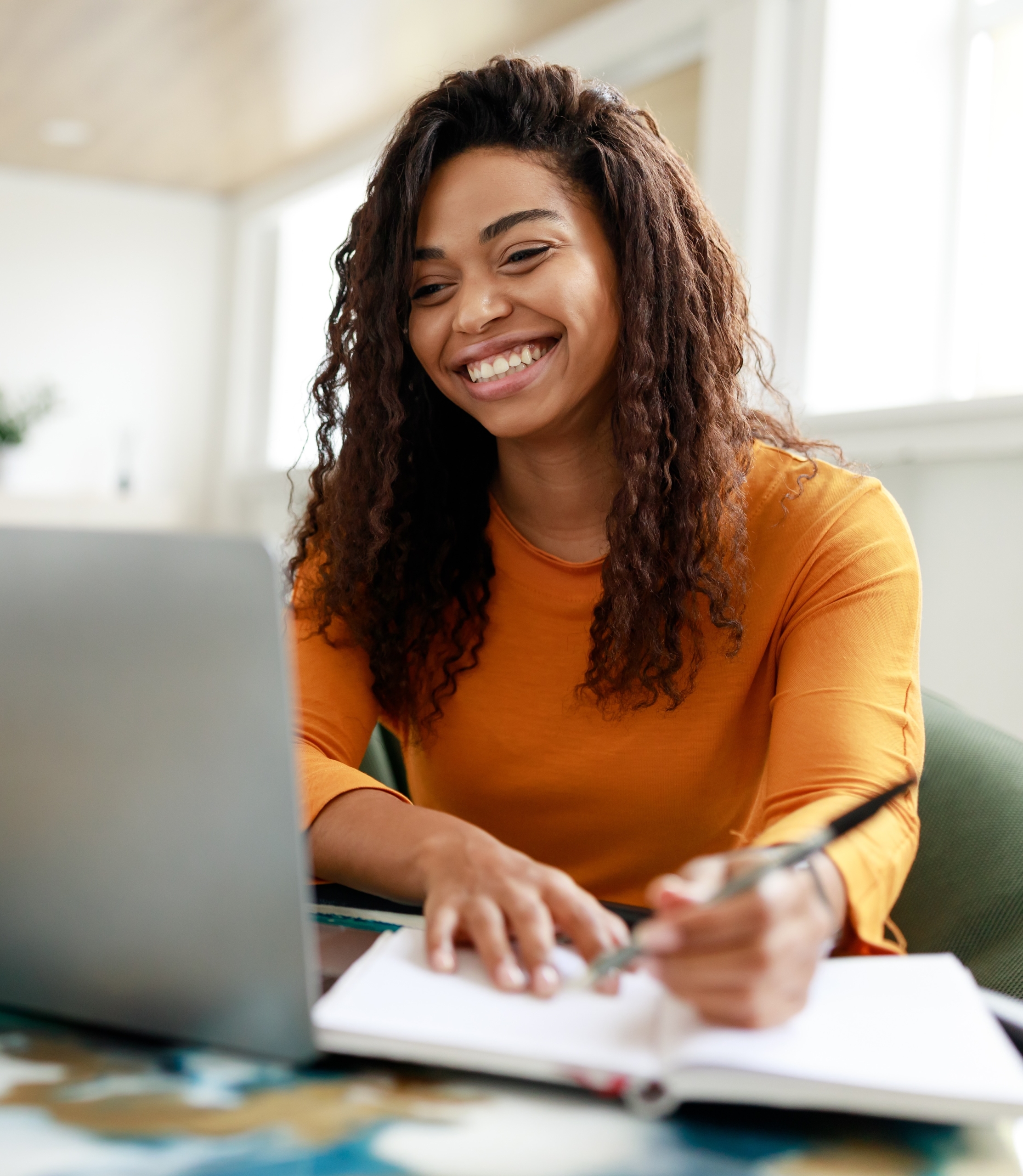 DistanceEducationPortraitOfSmilingWomanSittingAtDeskUsing | Patient Advocate and Care Manager Training Woman Online Learning