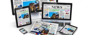 Modern computer media devices concept: desktop monitor, office laptop, tablet PC and black glossy touchscreen smartphones with internet web business news on screen and stack of color newspapers isolated on white background